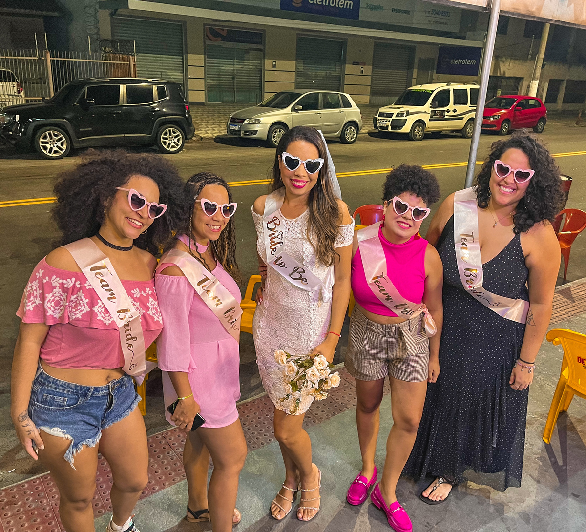 Todas nós na despedida de solteira, usando óculos de coração rosa e uma faixa